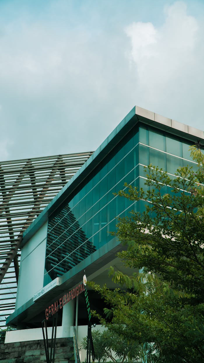 A modern building with a sleek glass facade and lush greenery in an urban setting.